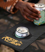 Close-up of RoosCamp Portable Camping Table built-in cup holder with drink can and RoosCamp logo on Oxford nylon surface