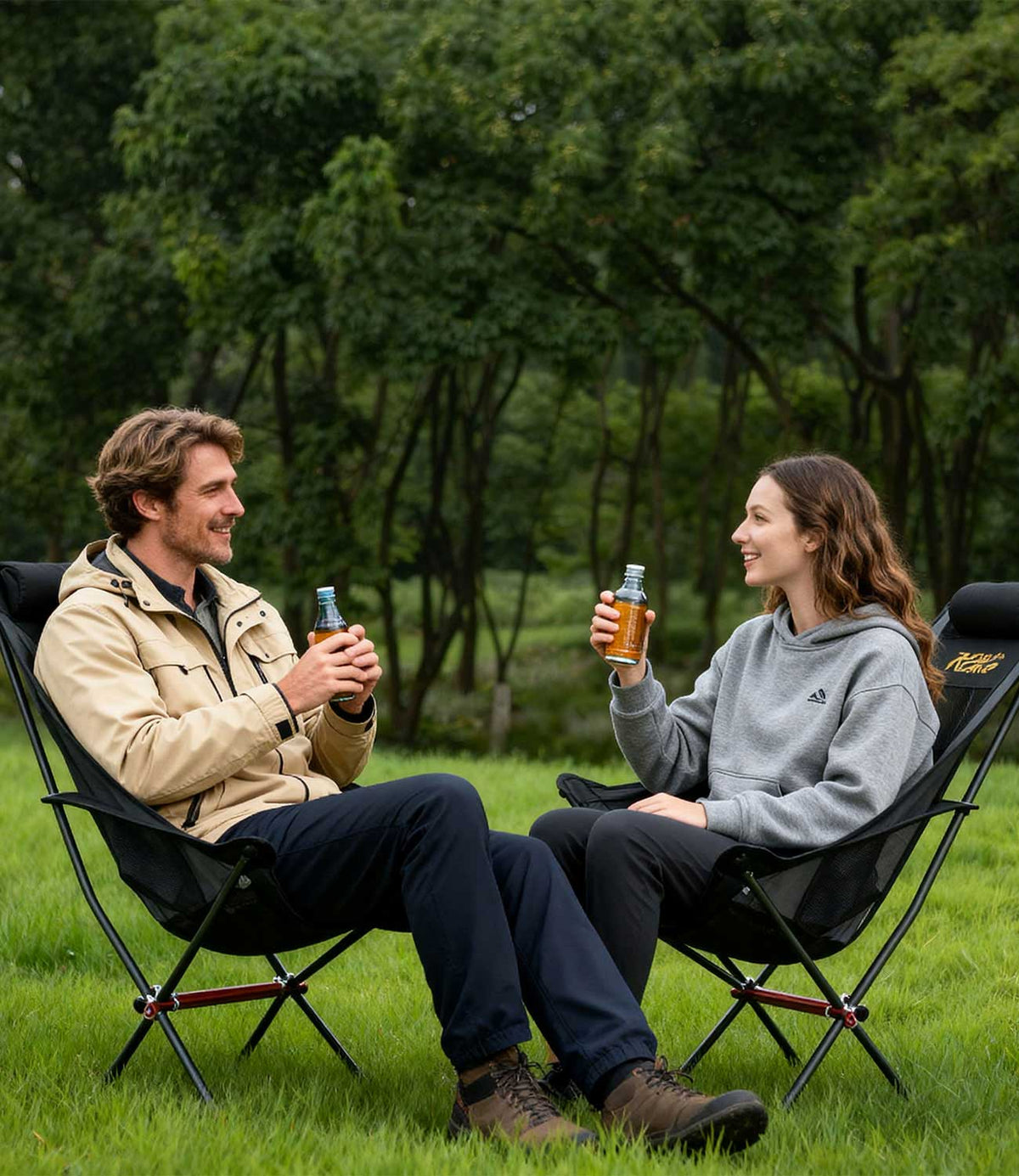 Couple relaxing in RoosCamp High-Back Camping Armchairs on grass in woodland setting