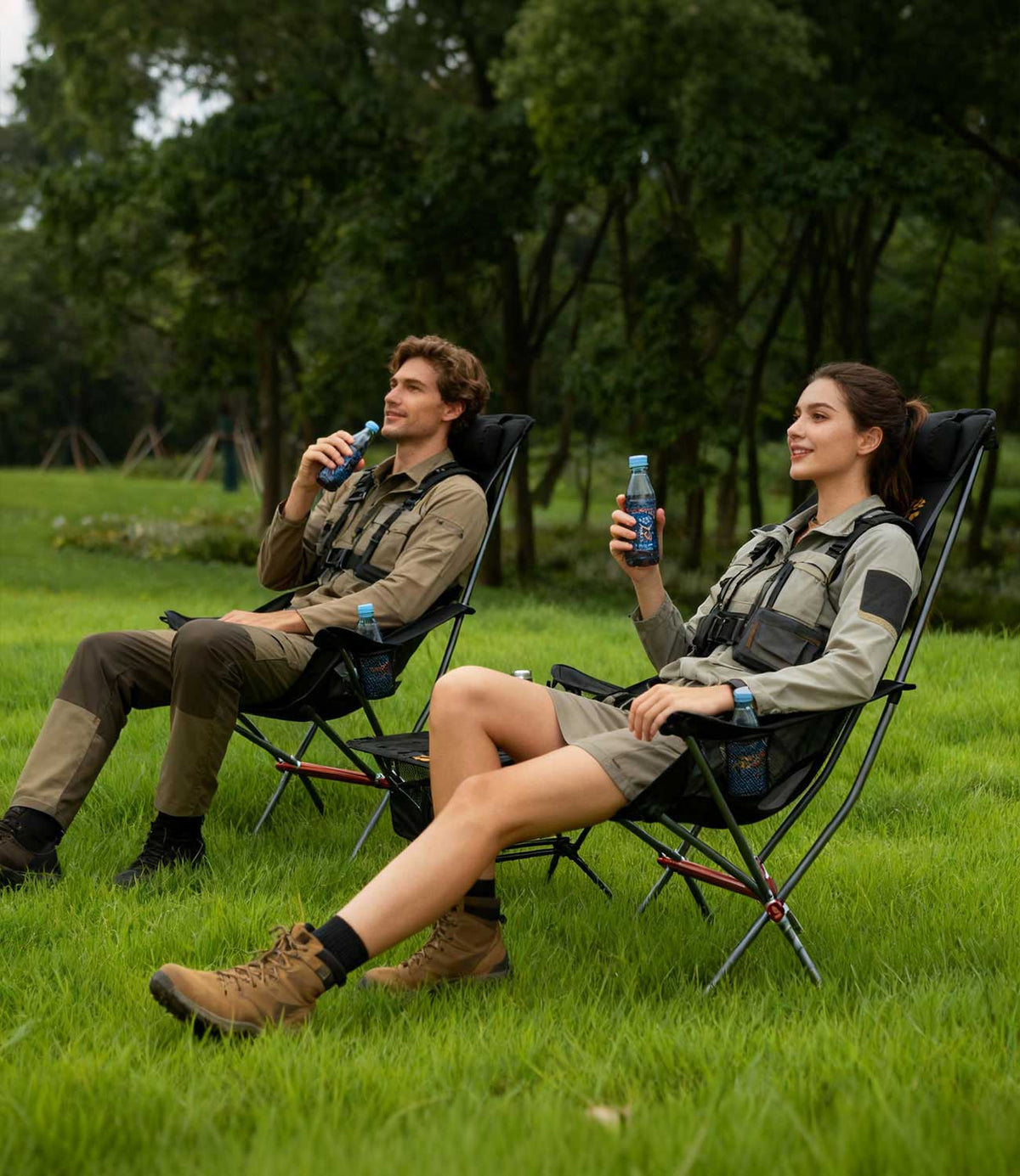 Two people in outdoor gear relaxing in RoosCamp High-Back Camping Armchairs on grass