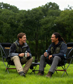 Two men laughing and relaxing in RoosCamp High-Back Camping Armchairs outdoors with drinks