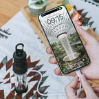RoosCamp RoosRepel 5000mAh power bank in use — device on camping blanket charging an iPhone via USB cable